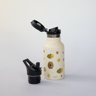 Cremefarbene Edelstahl-Trinkflasche mit Bienen-Motiven, Klappverschluss aufgesetzt, Strohhalmaufsatz daneben